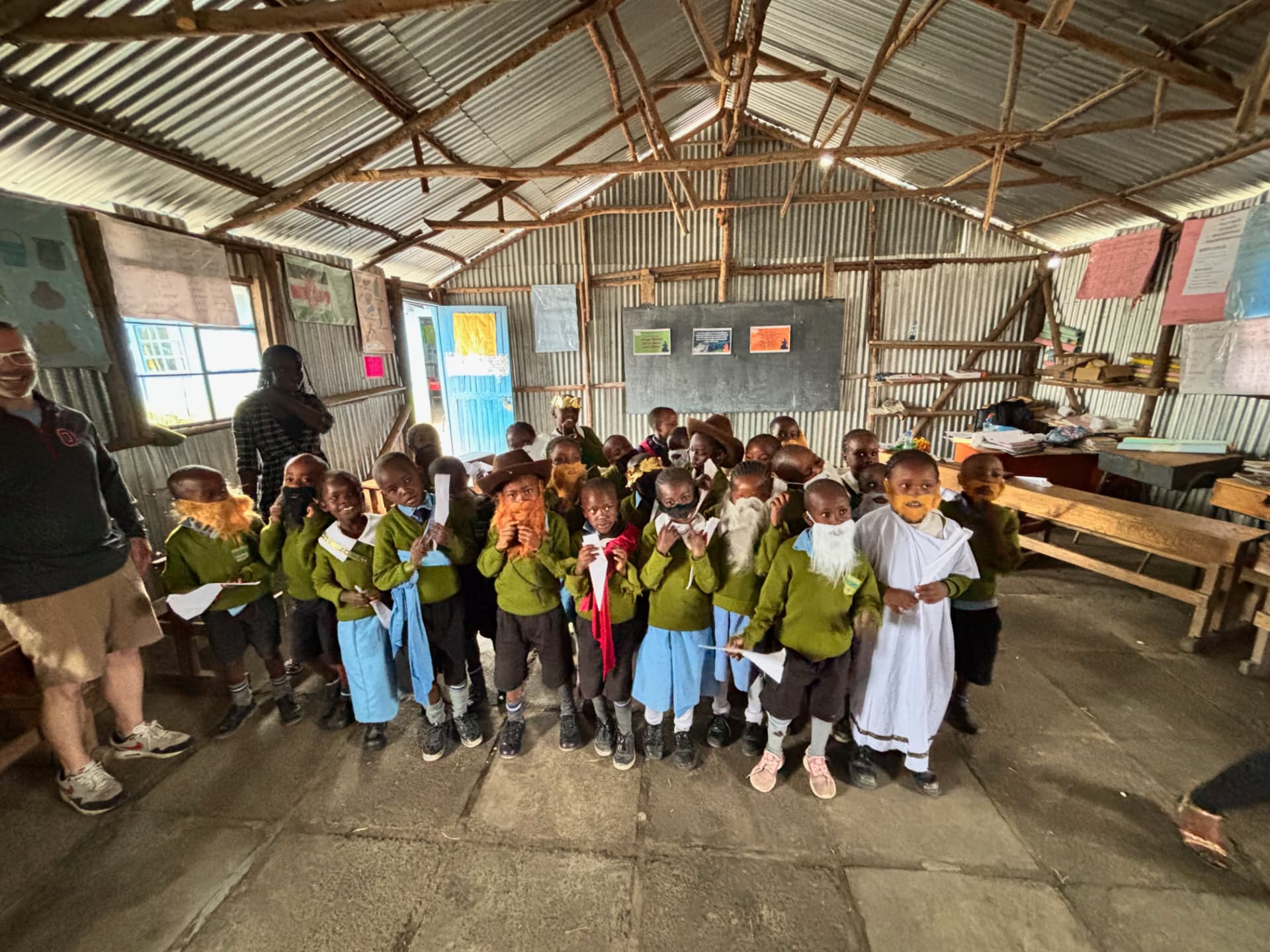 Young students in green sweaters performing a Christmas play in a classroom